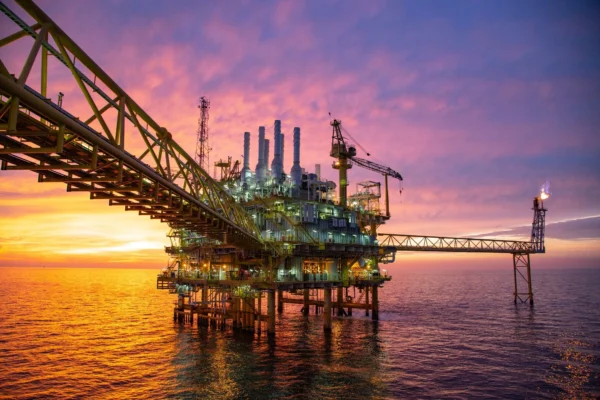 An offshore oil rig with a purple sky in the background.