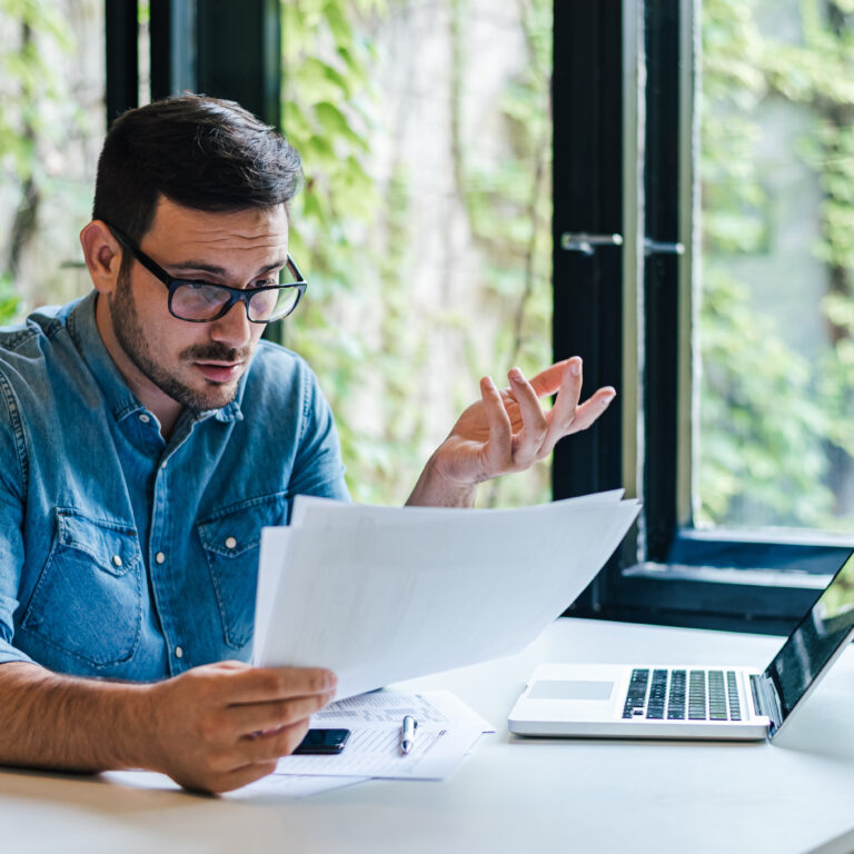Stressed looking man doing tax returns looking at documents