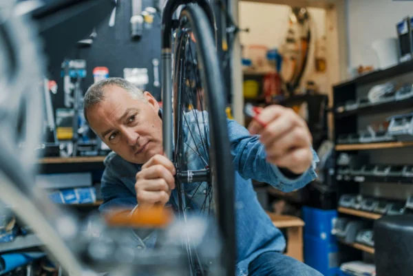 A business owner working on a bike wheel in his workshop. 