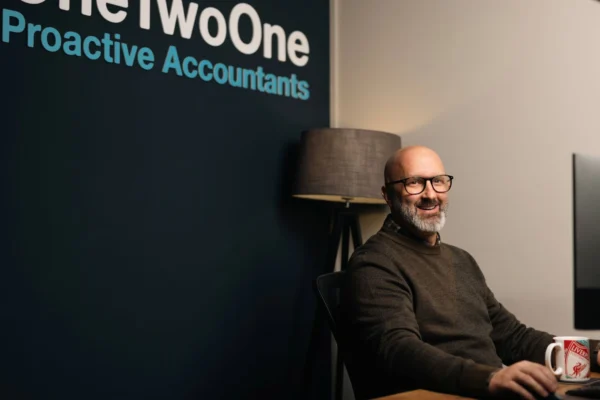 Jamie from One Two One Accounts smiling at his desk in an office setting.